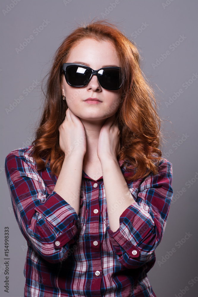 Portrait of a red-haired beautiful woman wearing sunglasses. Portrait of a red-haired beautiful woman wearing sunglasses.