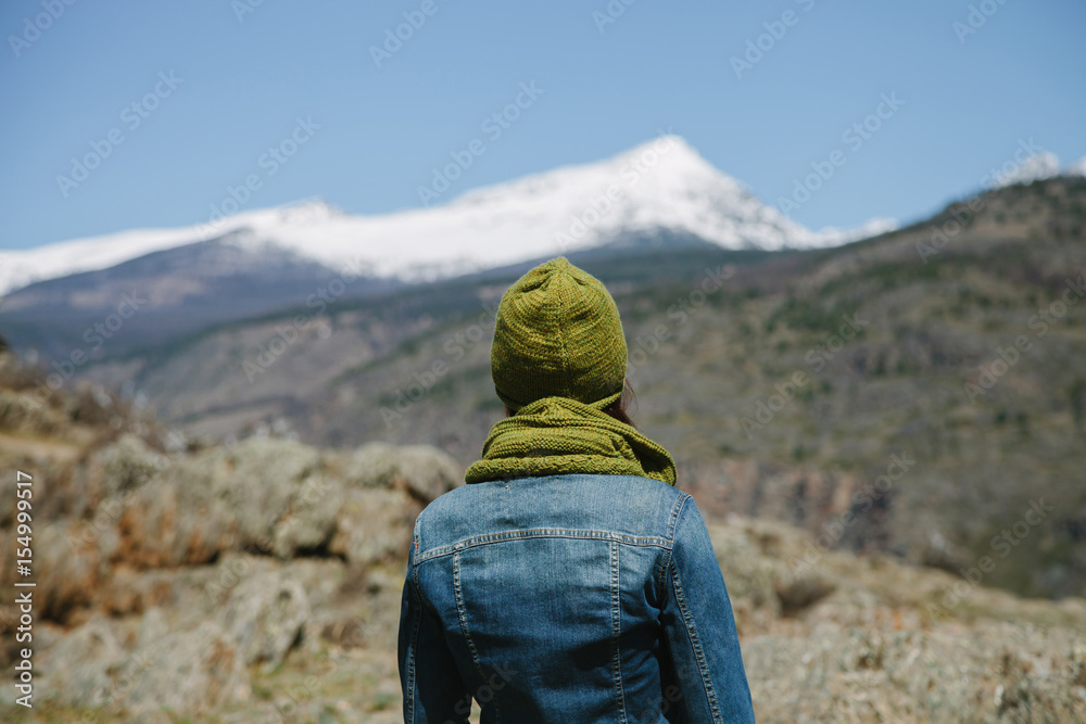 Young woman looking at mountains. Photo from behind