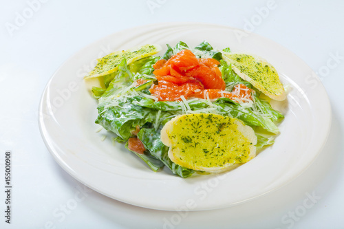 fresh caesar salad with salmon on white plate