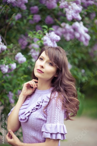 Young beautiful woman walks along the spring garden. A girl stands near the lilacs. Lilac. Flowers.