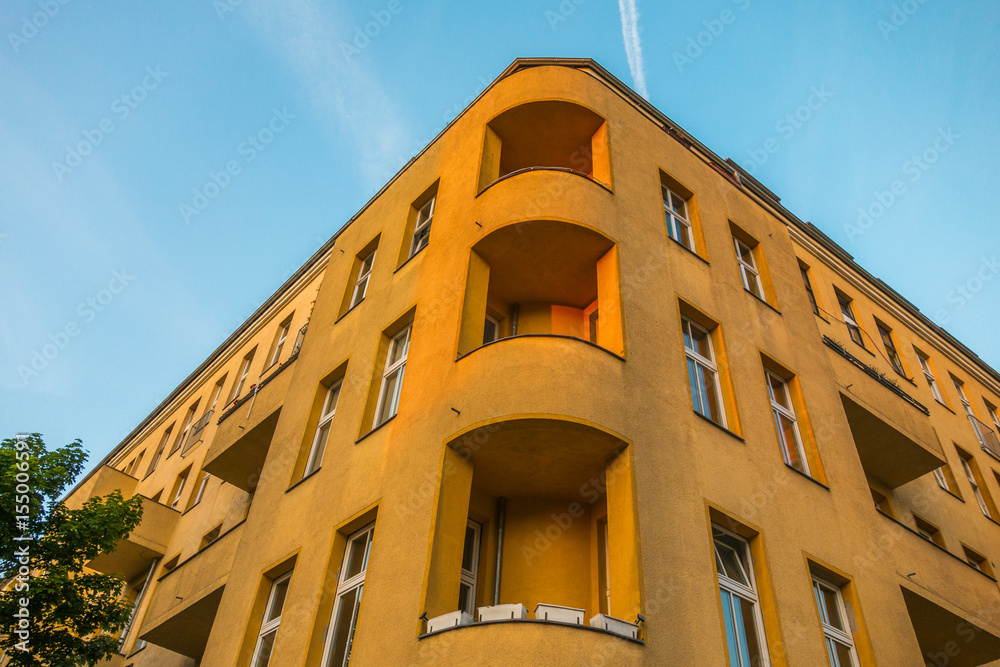 Fototapeta premium yellow facaded corner house with curved balconies