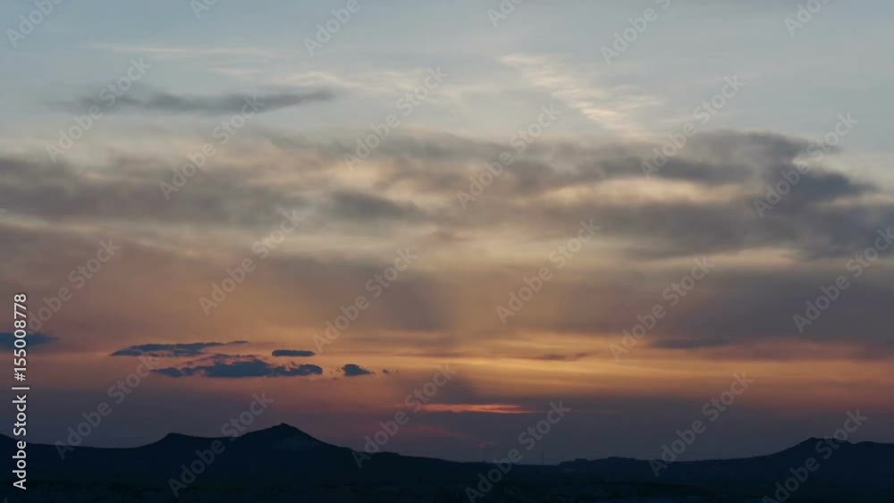 Time Lapse, Bright orange fiery sun slips behind silhouetted mountains as thick clouds turn vibrant red, orange at sunset Time Lapse, Bright orange fiery sun slips behind silhouetted mountains as thick clouds turn vibrant red, orange at sunset