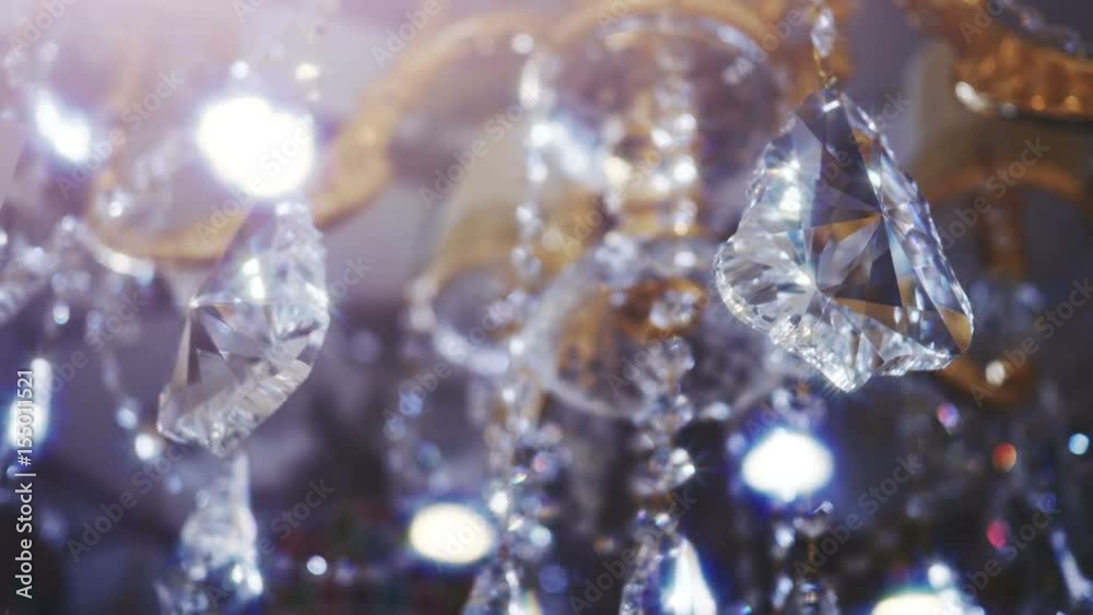 Classic triangle shape crystals. 
Close up on two big beautiful crystals of a luxury chandelier. With bling bling shining reflection. Many small crystals and bokeh at the back. 
