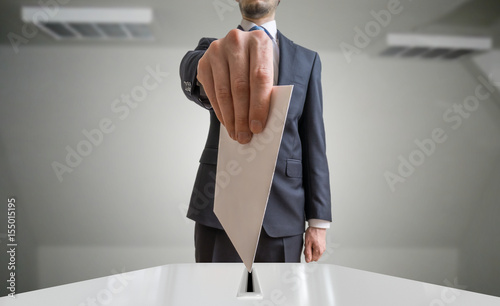 Election and democracy concept. Voter holds envelope or paper in hand above ballot. photo