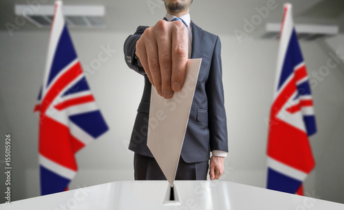 Election or referendum in Great Britain. Voter holds envelope in hand above ballot. United kingdom flags in background. photo
