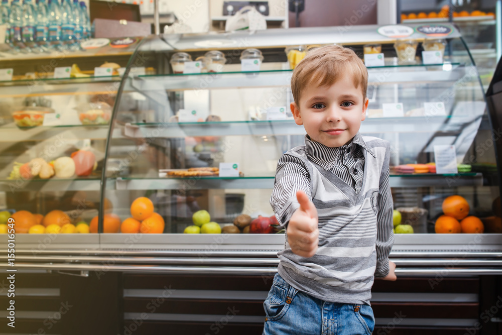 Φωτογραφία A little boy stands near a showcase And shows the thumb