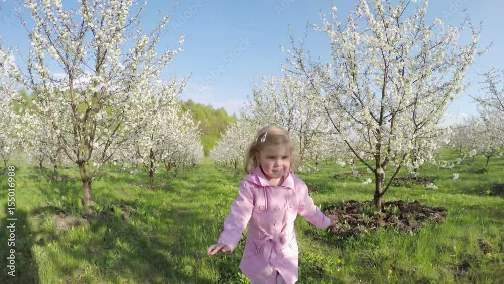 Sweet little curly girl in pink raincoat running away in the garden Sweet little curly girl in pink raincoat running away in the garden