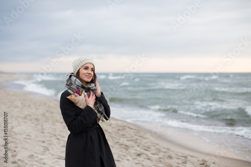 Woman with a bouquet of flowers in the spring at sea in a cap winter cold romance