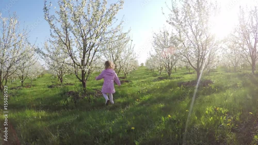 Sweet little curly girl in pink raincoat running away in the garden Sweet little curly girl in pink raincoat running away in the garden