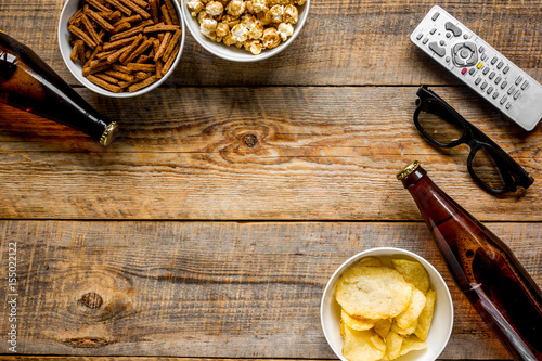 film whatching party with beer, crumbs, chips and pop corn wooden background top view mockup photo