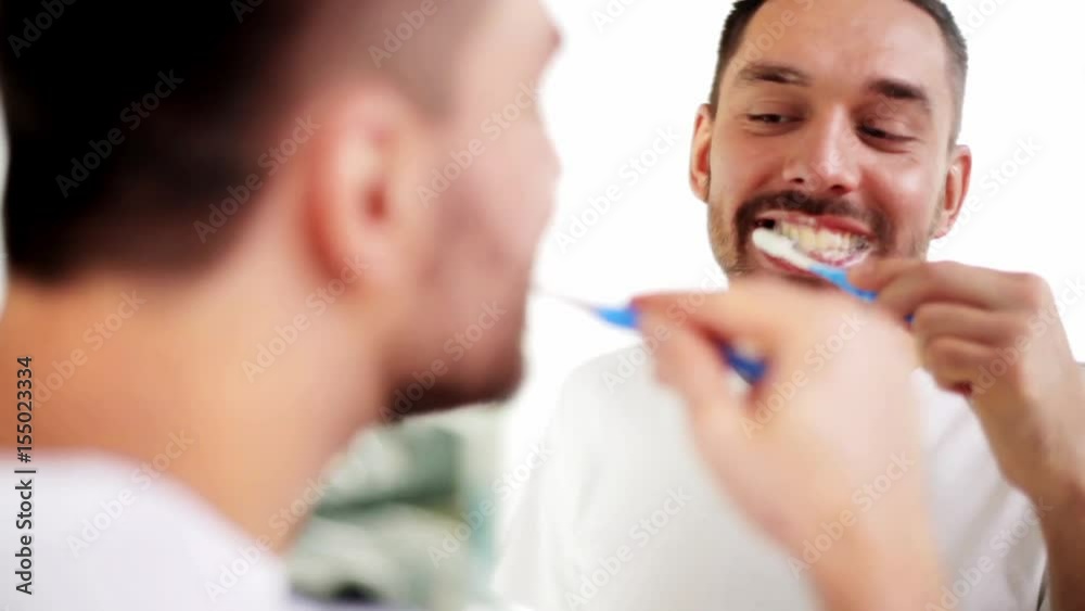 man with toothbrush cleaning teeth at bathroom