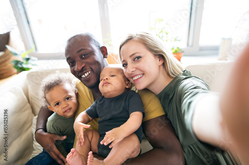 Young interracial family with little children taking selfie.