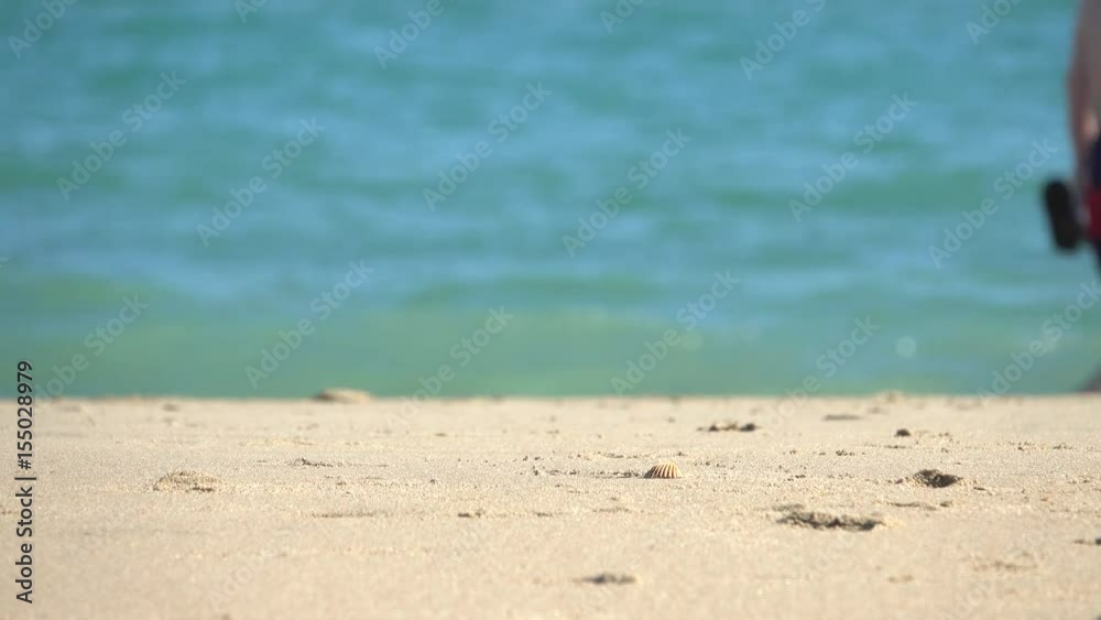 Adults walking along the shore. Sand of the border focused, on background of the sea de-focused. Adults walking along the shore. Sand of the border focused, on background of the sea de-focused.