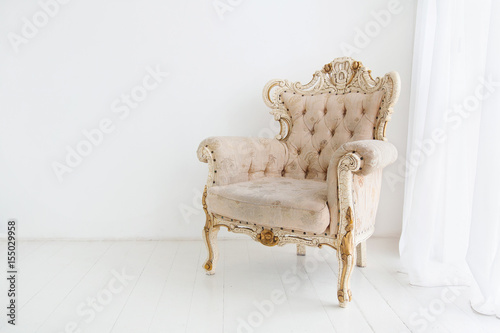 Vintage armchair against white wall in white room. Space for your copy