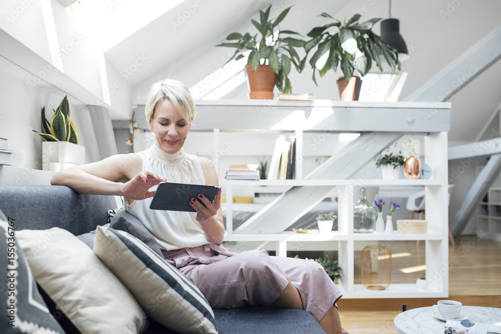Pretty Caucasian woman sitting on couch at living room and enjoying reading magazine. Pretty Caucasian woman sitting on couch at living room and enjoying reading magazine.