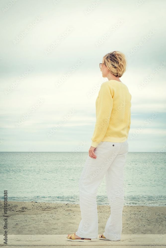 Full length portrait of young woman looking through the sea alone. Rear view Full length portrait of young woman looking through the sea alone. Rear view