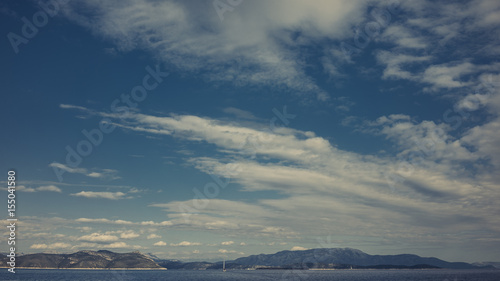 Segelboot segelt durch Insellandschaft im Meer bei blauem Himmel mit Wolken