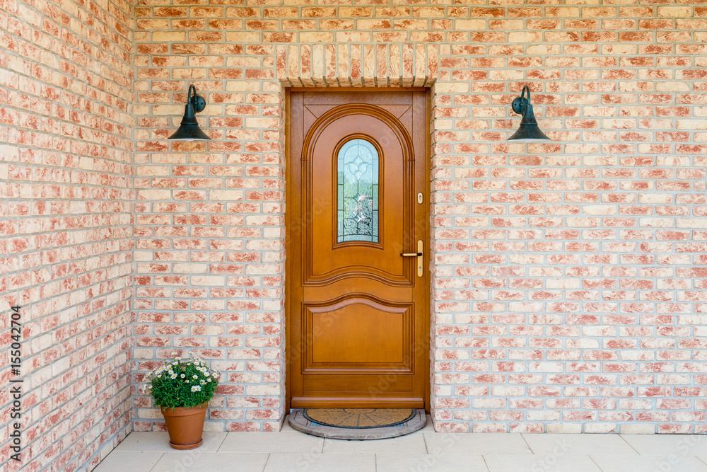 Naklejka premium Stylish wooden front - entrance door in a detached house - embedded in a brick wall