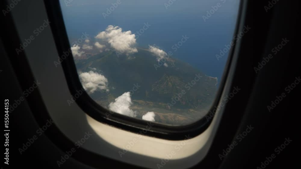 View through an airplane window on the tropical island, ocean, sky and clouds. Aerial view sea, clouds and sky as seen through window of an aircraft. 4K video. Aerial footage. Travel concept. View through an airplane window on the tropical island, ocean, sky and clouds. Aerial view sea, clouds and sky as seen through window of an aircraft. 4K video. Aerial footage. Travel concept.