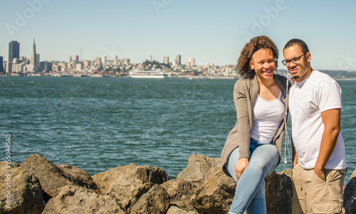 Brother and sister sitting on rocks at Treasure Island with San Francisco in background view