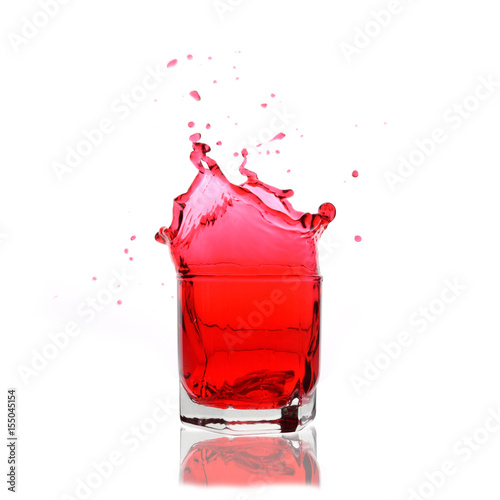 Red cocktail splashing on a glass on white background