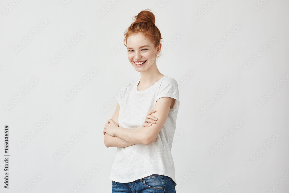 Fototapeta premium Portrait of cheerful young redhead girl laughing with crossed arms.