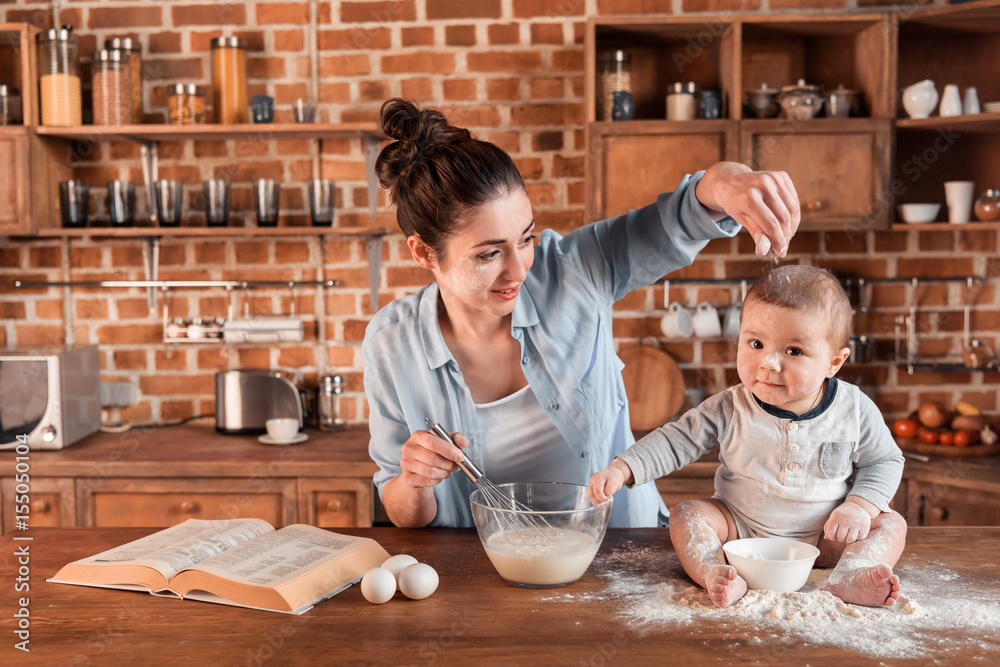 Happy mother with her son preparing dough for cookies and having fun together at the kitchen Happy mother with her son preparing dough for cookies and having fun together at the kitchen