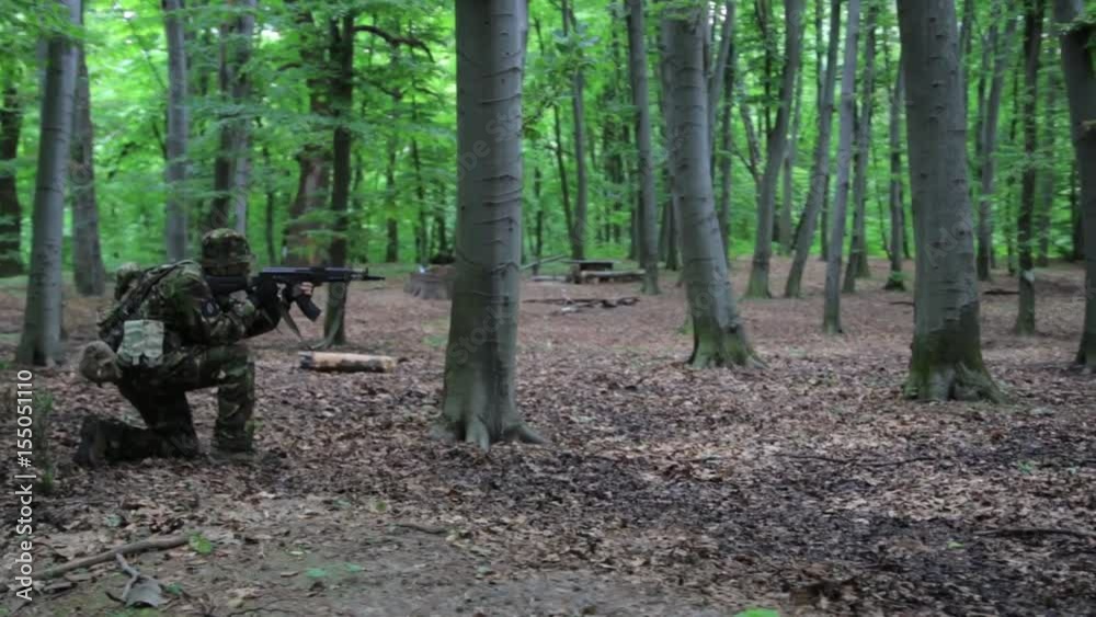 Guerilla partisan warrior aiming in forest ambush carrying his gun. War battlefield maneuvers training. Guerilla partisan warrior aiming in forest ambush carrying his gun. War battlefield maneuvers training.