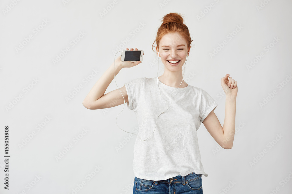 Obraz premium Beautiful redhead girl listening music in headphones laughing.