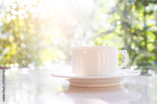 White coffee cup on the table with the sun as a backdrop.