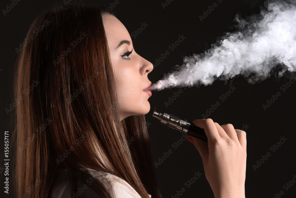 Fototapeta premium The face of vaping young woman at black studio
