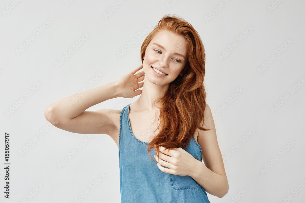 Attractive redhead model smiling touching hair. Attractive redhead model smiling touching hair.