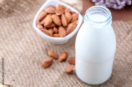 Almond milk in glass bottle on wood background