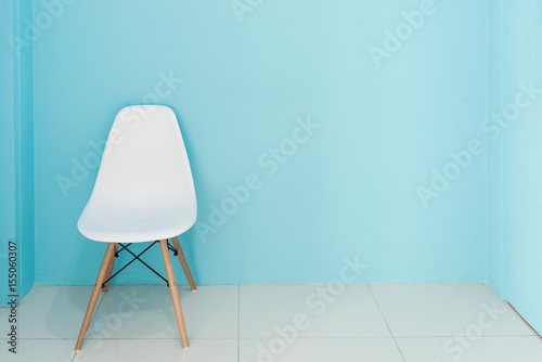 Modern white chair in a living room with blue wall with empty space for interior decorating or copyspace background.