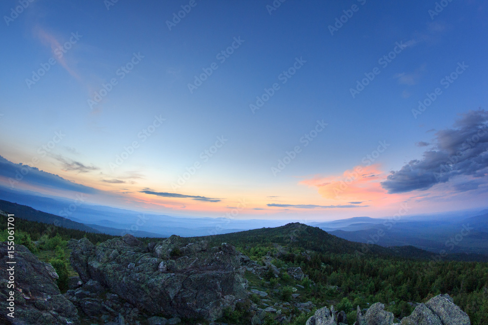 Sunset over the mountainous terrain. The nature of the Southern Urals. Sunset sky over the forest and the mountains.