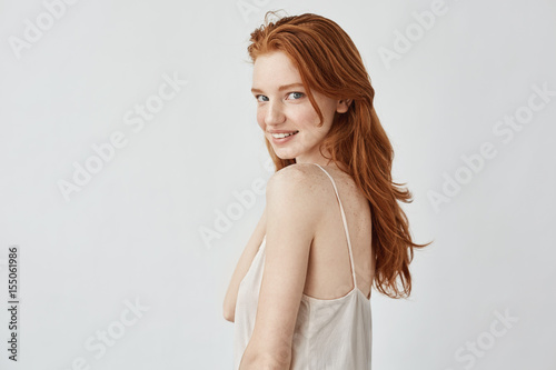 Beautiful redhead model with freckles smiling looking at camera.