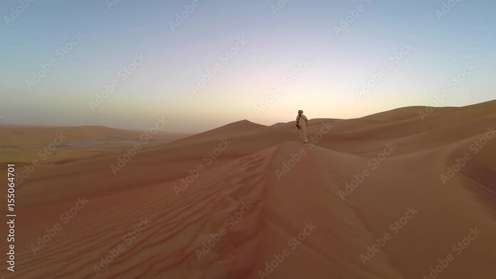 Man walking up sand dunes of Liwa desert Man walking up sand dunes of Liwa desert