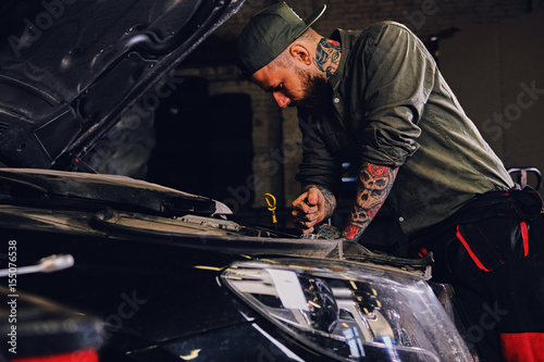 Mechanic inspecting car's engine in a workshop.