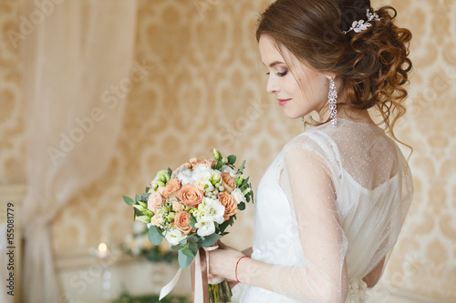 Pretty young Bride. Boudoir morning of the bride. Looking on her bouquet