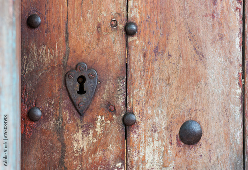 Heart shaped keyhole surround in old wooden door.