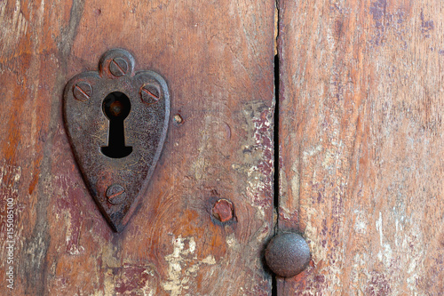 Heart shaped keyhole surround in old wooden door.