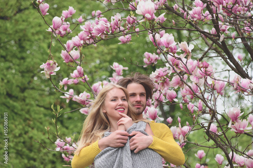 girl and guy, couple in love in spring magnolia flowers