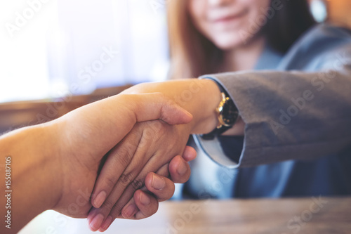 Business image of businesswoman and businessman shaking hand to each other in office