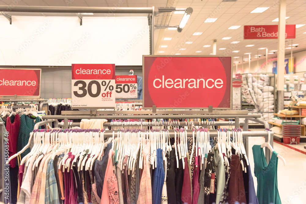 Red clearance sign for 30% off on cloth rack with variety of women apparel in retail store in America. - obrazy, fototapety, plakaty 