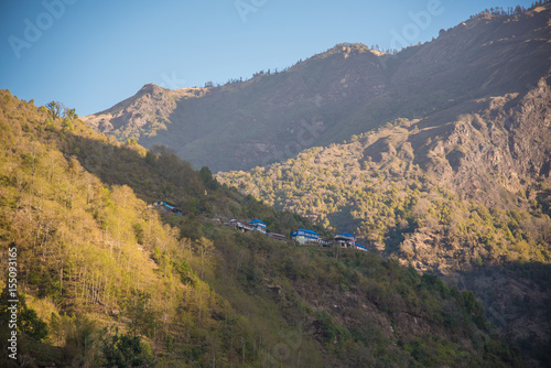 Nepal Snowy mountainPanoramic view from the mountain top showing green valleys, hills, misty clouds, and a scenic village in the landscape photo