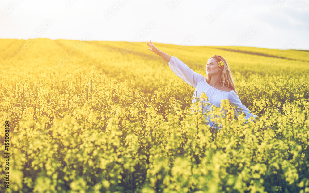 Smiling woman in yellow rapeseed field at sunny day Smiling woman in yellow rapeseed field at sunny day