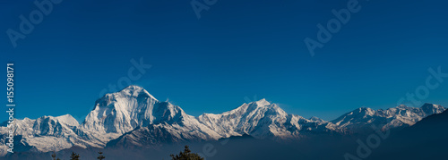 A panoramic view of snow-covered mountains in winter with clear blue skies in the Alps