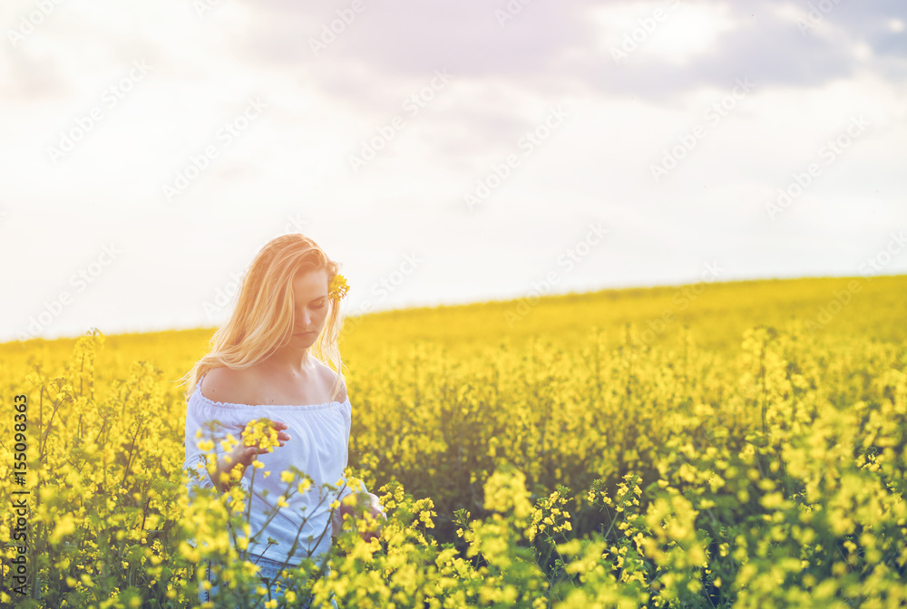 Smiling woman in yellow rapeseed field at sunny day Smiling woman in yellow rapeseed field at sunny day