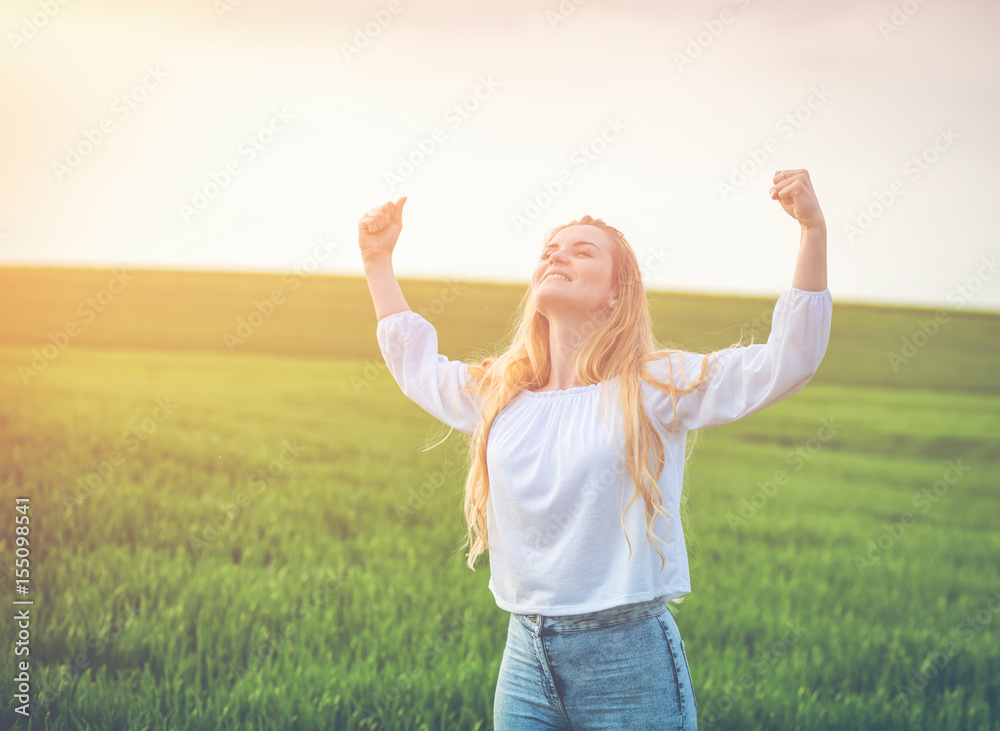 Happy smiling woman in green field at summer day success concept