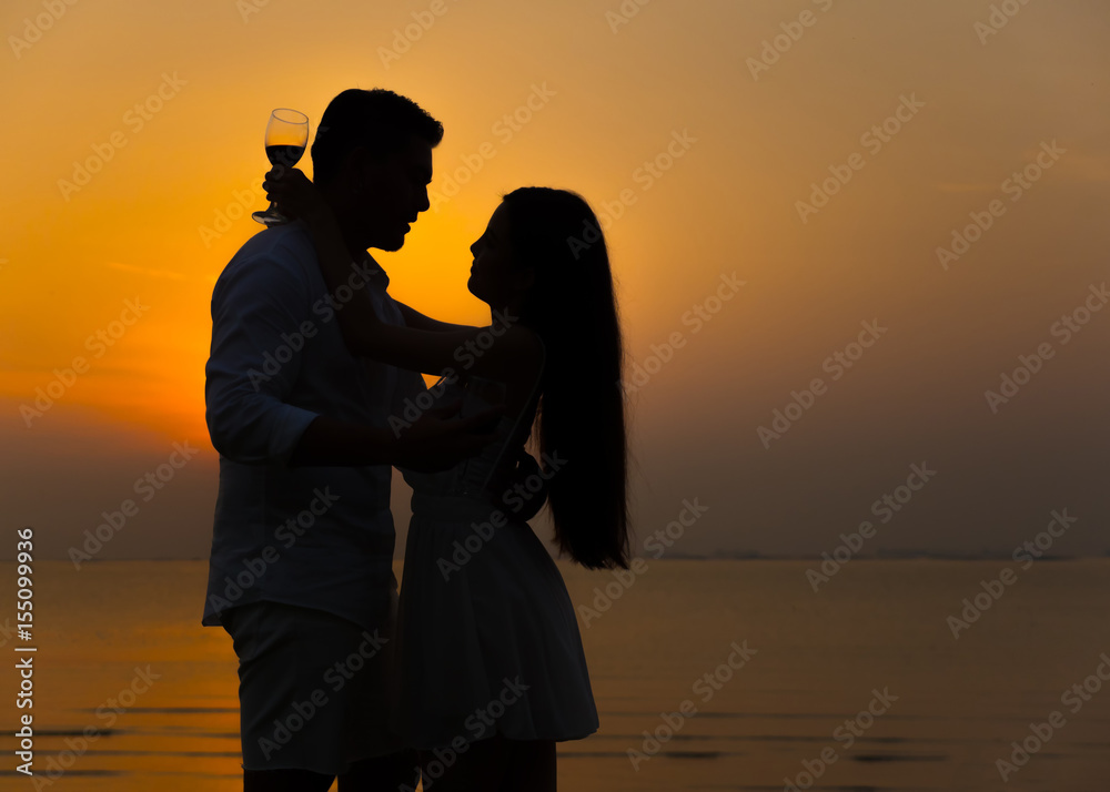 Romantic couple enjoying glass of wine against a beautiful sunset. Love and holiday concept.